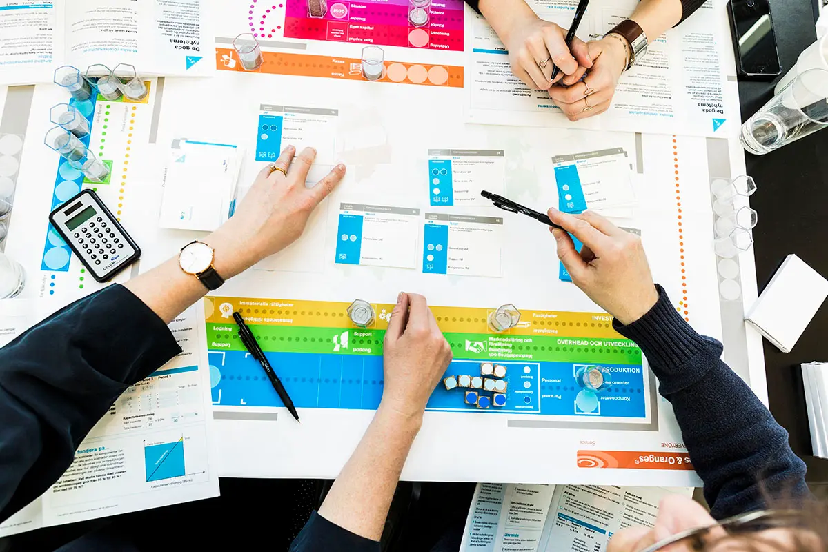 Top view of people playing CELEMI Apples and Oranges™ business simulation